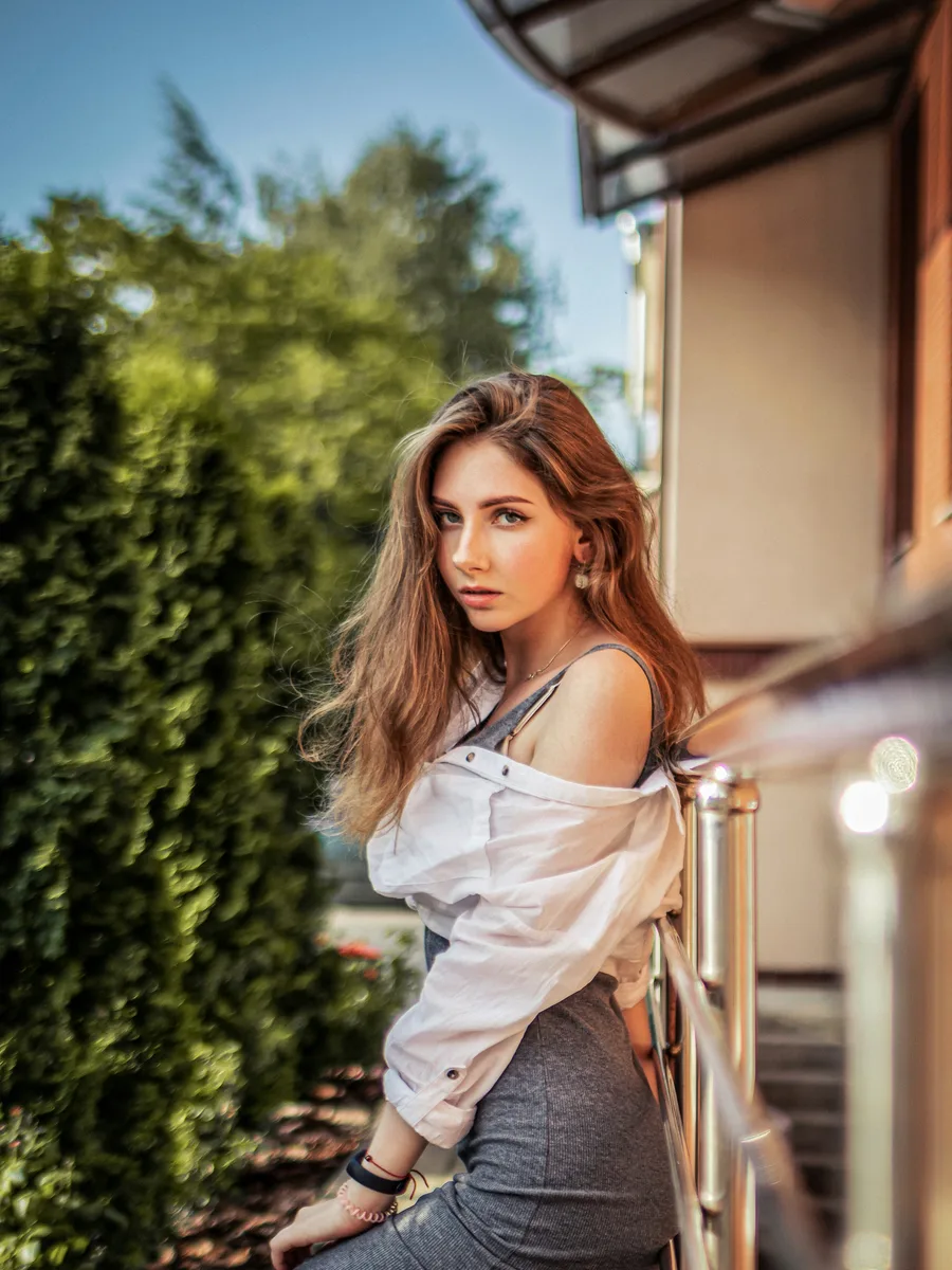 Original photo — a woman with straight hair in a white top leaning on an outdoor railing