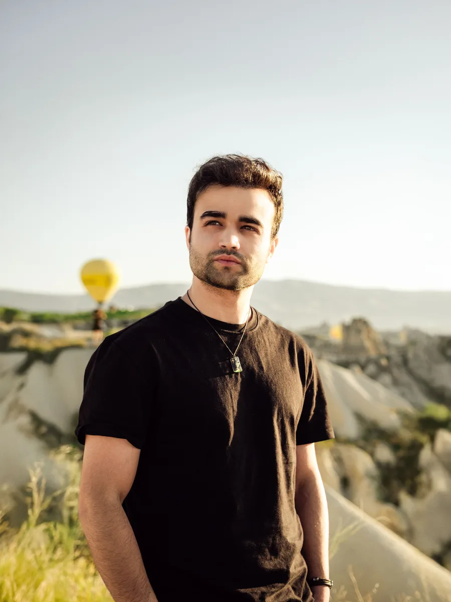 Original photo — a man in a black t-shirt standing in a dry field