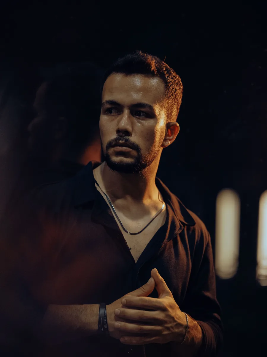Original photo — a man with dark hair in a dark shirt, low indoor light