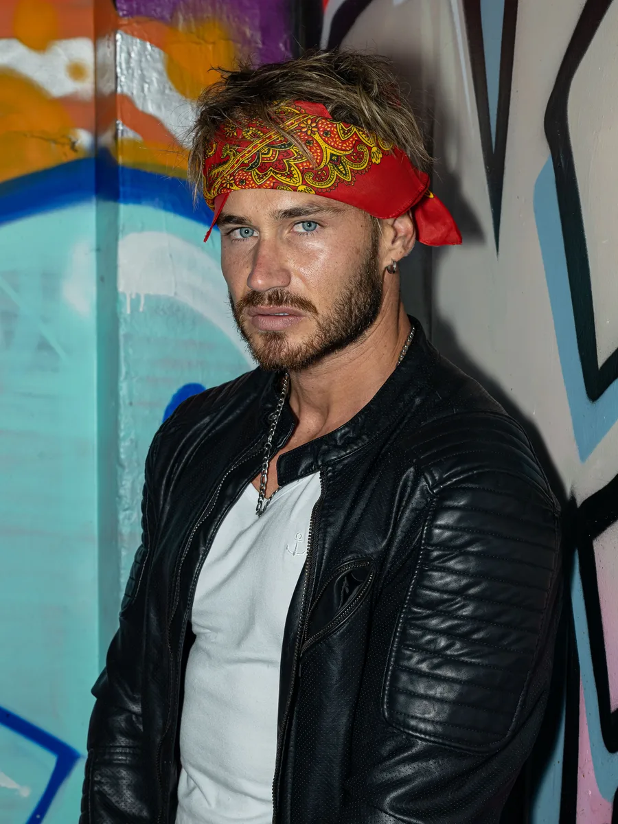 Original photo — a man in a red bandana and black leather jacket against a graffiti wall