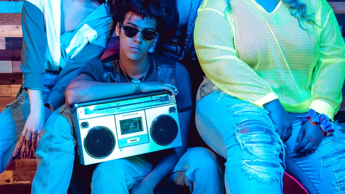 A group of friends around a retro boombox under neon light