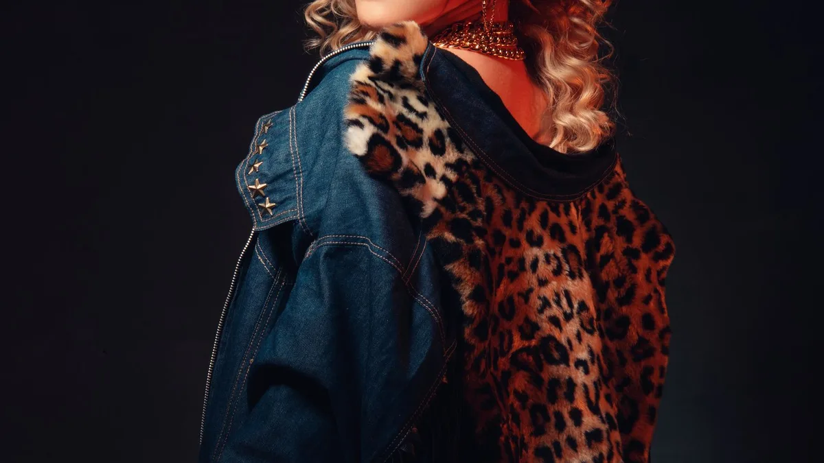 A blonde woman in denim and leopard print with dramatic 80s-style lighting