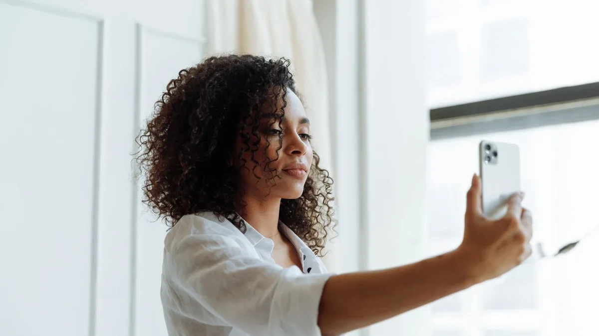 A woman with curly hair taking a selfie indoors