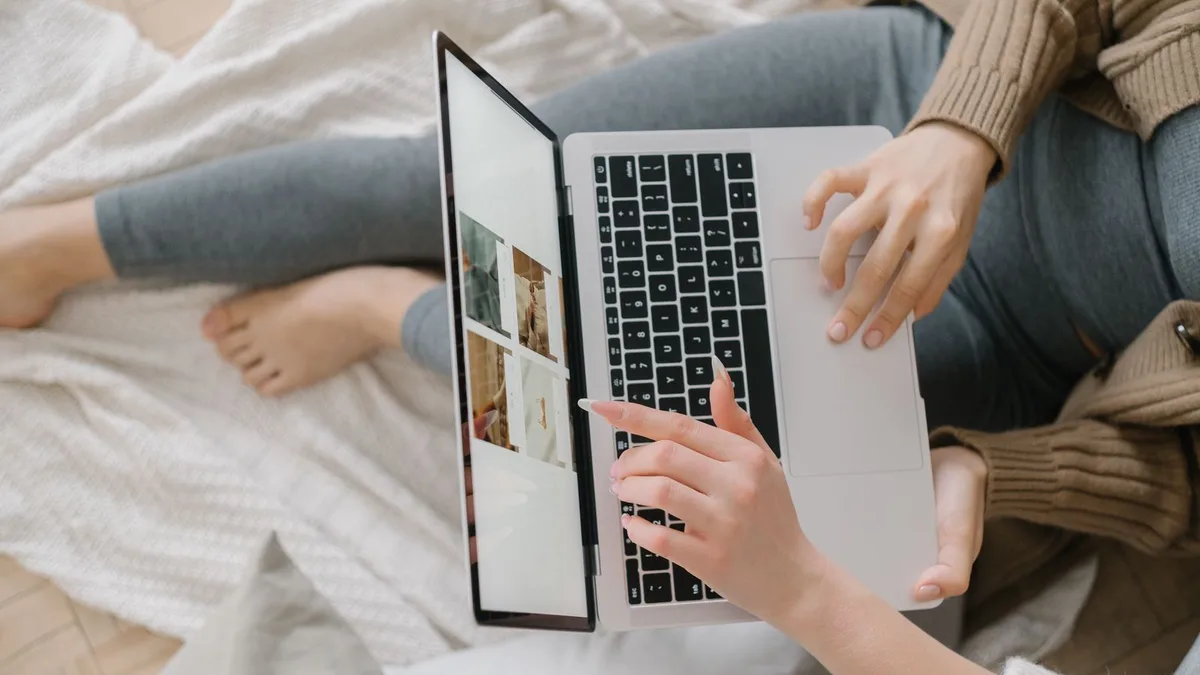 A woman relaxing on a bed while browsing on a laptop