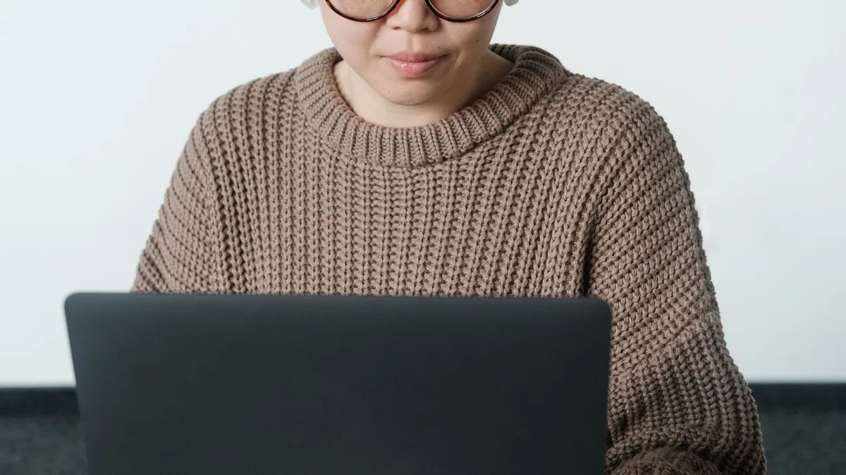 A woman wearing glasses focused on a laptop screen indoors
