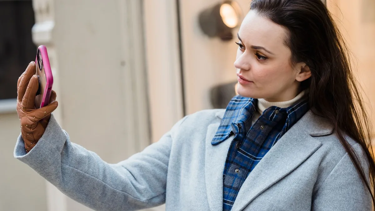 A woman taking a self-portrait photo on a city street