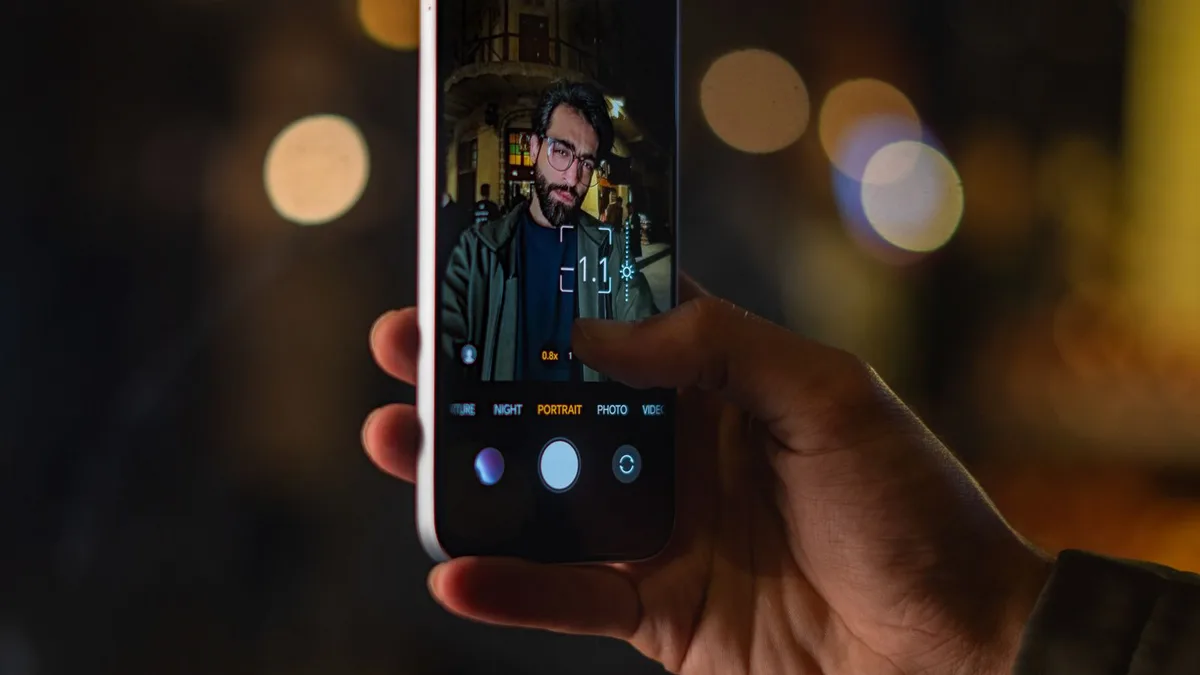 A man taking a nighttime selfie video with city lights in the background