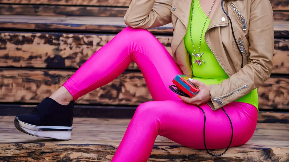 A person in pink retro sportswear holding a cassette player