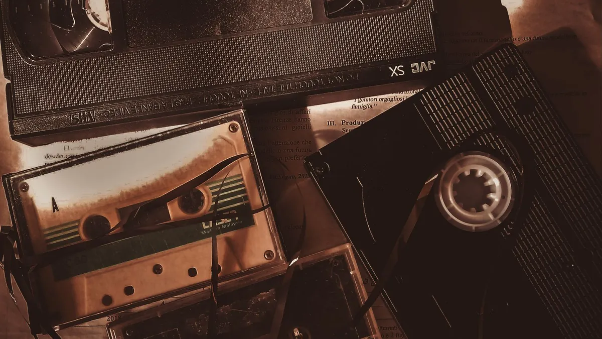 A sepia-toned flat lay of VHS and cassette tapes