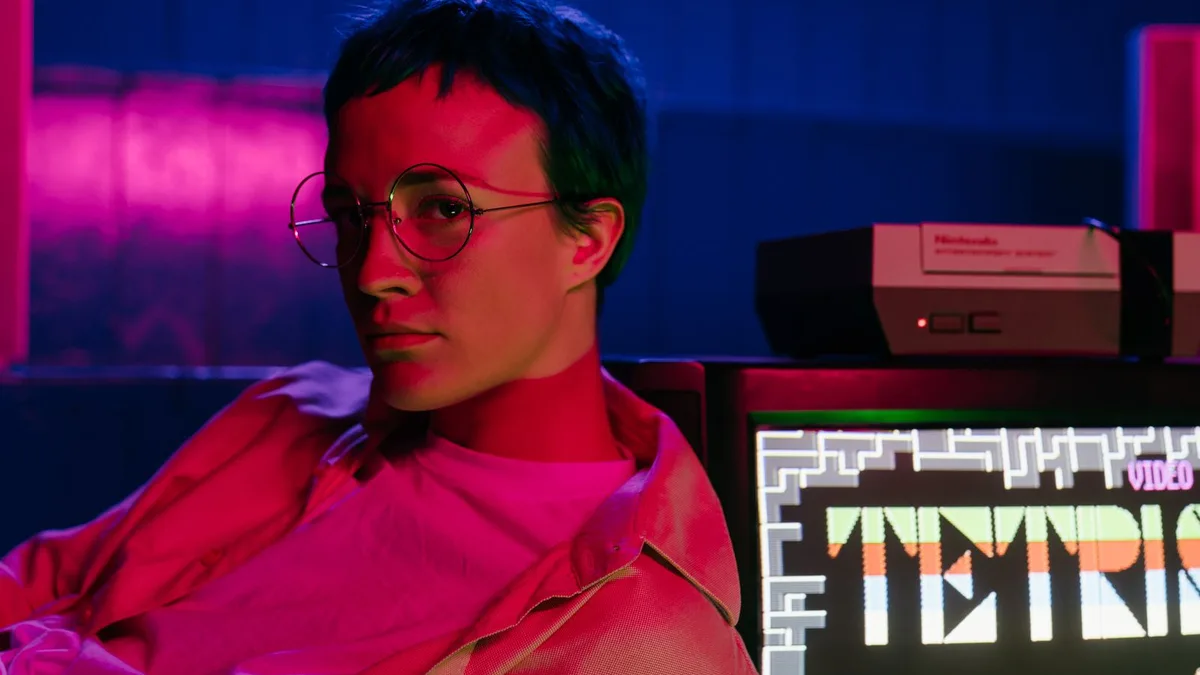 A teenager with glasses at a retro arcade with a Tetris game screen